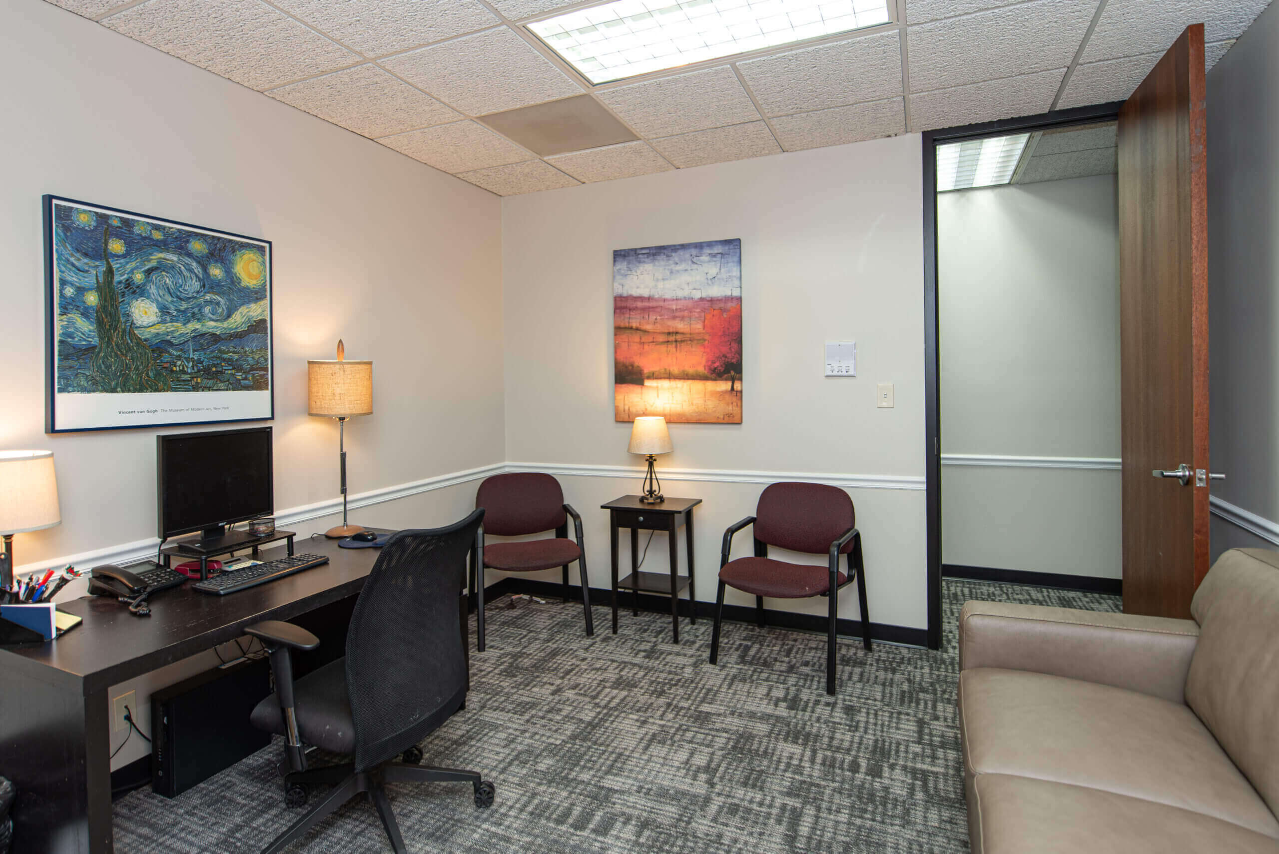 A room with two chairs, a desk and a television.