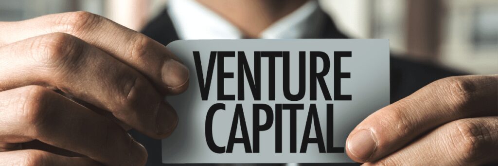Man holding card with "Venture Capital" text.